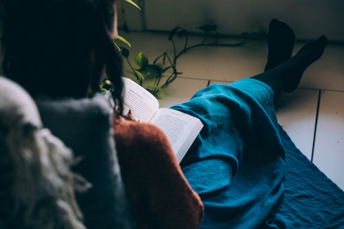 Woman contented reading a book alone, cozied up on the floor